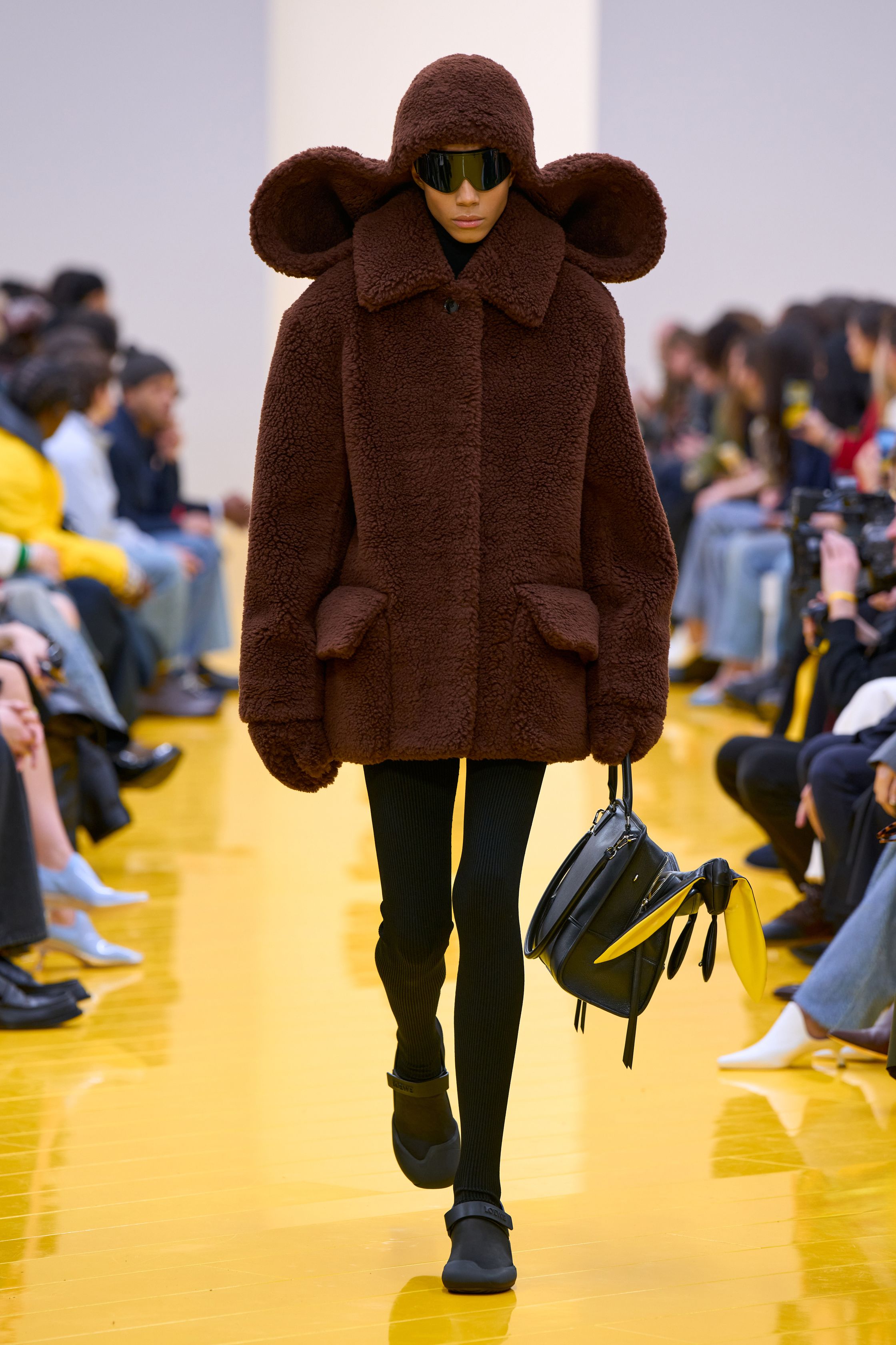 Jonathan Anderson 为 Loewe 带来一场充满艺术实验的秀：黄色地面与鲜明色彩形成强烈视觉舞台，极简廓形针织、雕塑化皮革外套、夸张毛绒结构和实验比例裙装共同构建一种“可穿戴雕塑”。从鲜黄、亮蓝到浓郁棕色毛绒，材质对比成为本季核心语言，既有幽默感也带有博物馆式艺术气质-顽石频道趋势研究